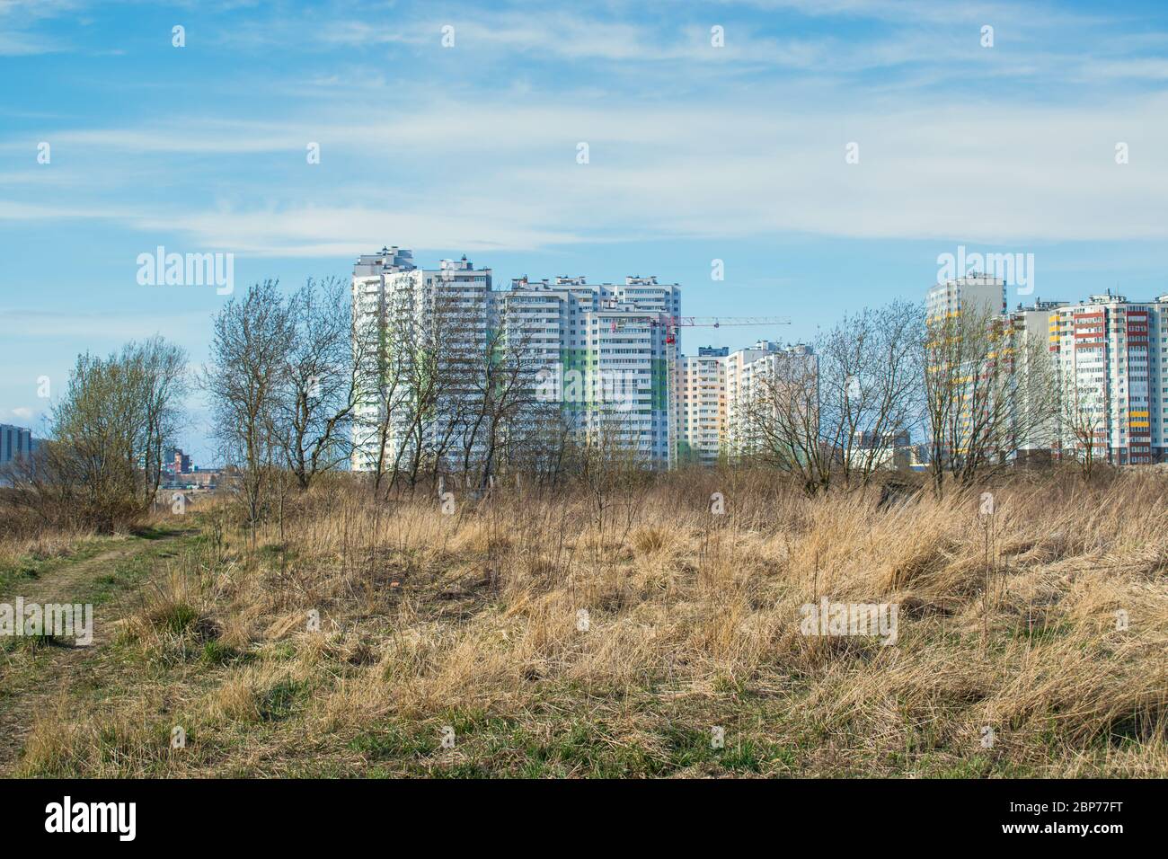 Costruzione di appartamenti a più piani in un terreno vuoto e incolto di erba. Sviluppo di un ex campo agricolo da un comp. Di costruzione Foto Stock