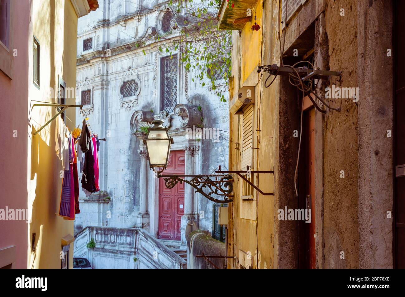 Lampada da strada e lavanderia in una pittoresca strada stretta di Alfama nella città vecchia di Lisbona, Portogallo Foto Stock