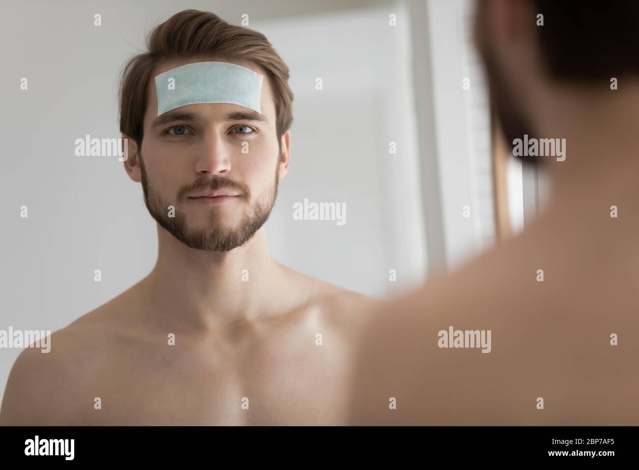 Ritratto di giovane uomo usa la patch anti-rughe sulla fronte Foto Stock