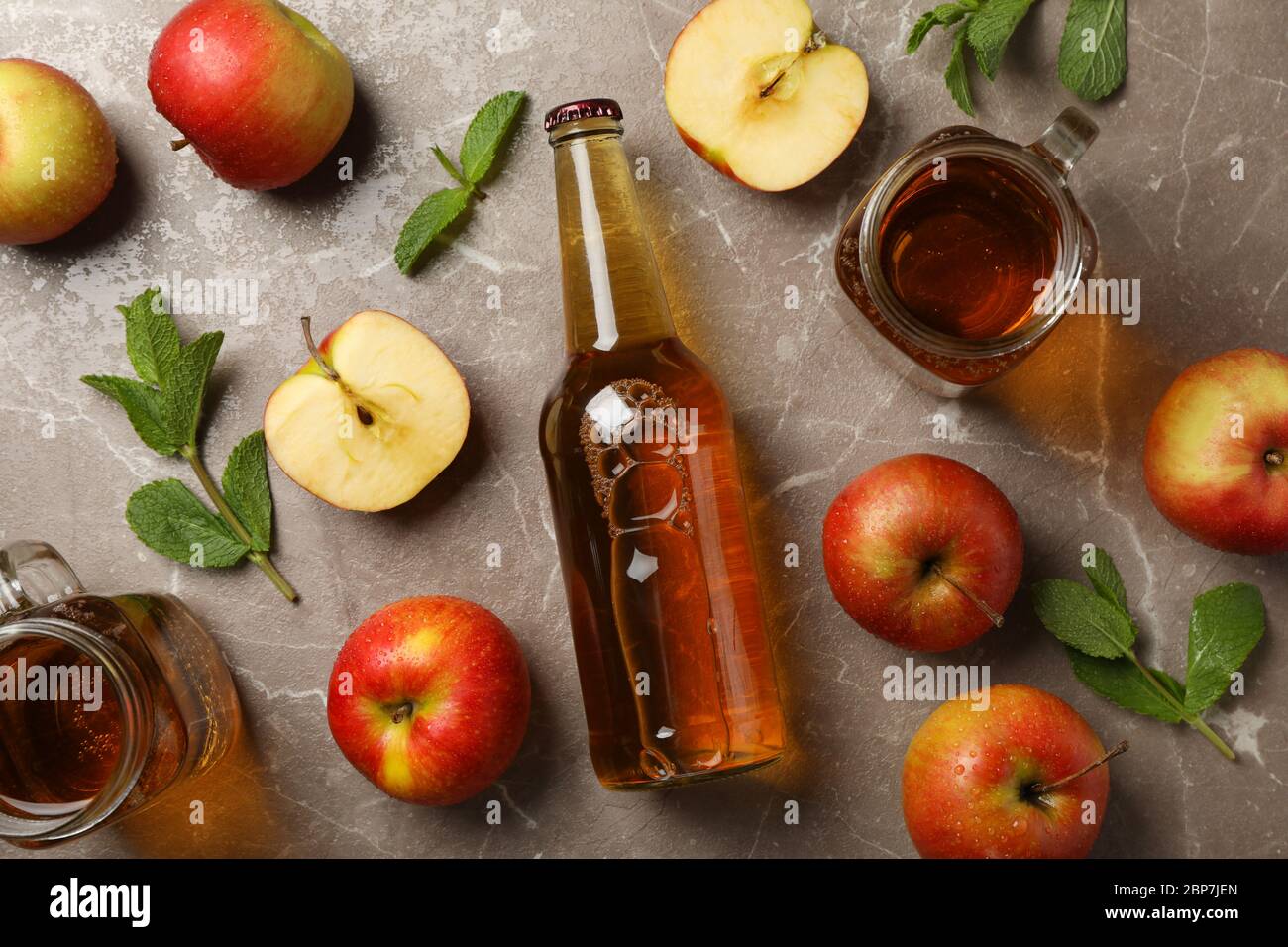 Composizione con sidro e mele su sfondo grigio Foto Stock