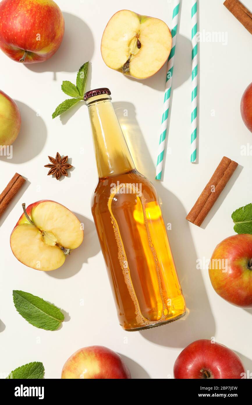 Composizione con sidro, mele, paillette e cannella su sfondo bianco Foto Stock