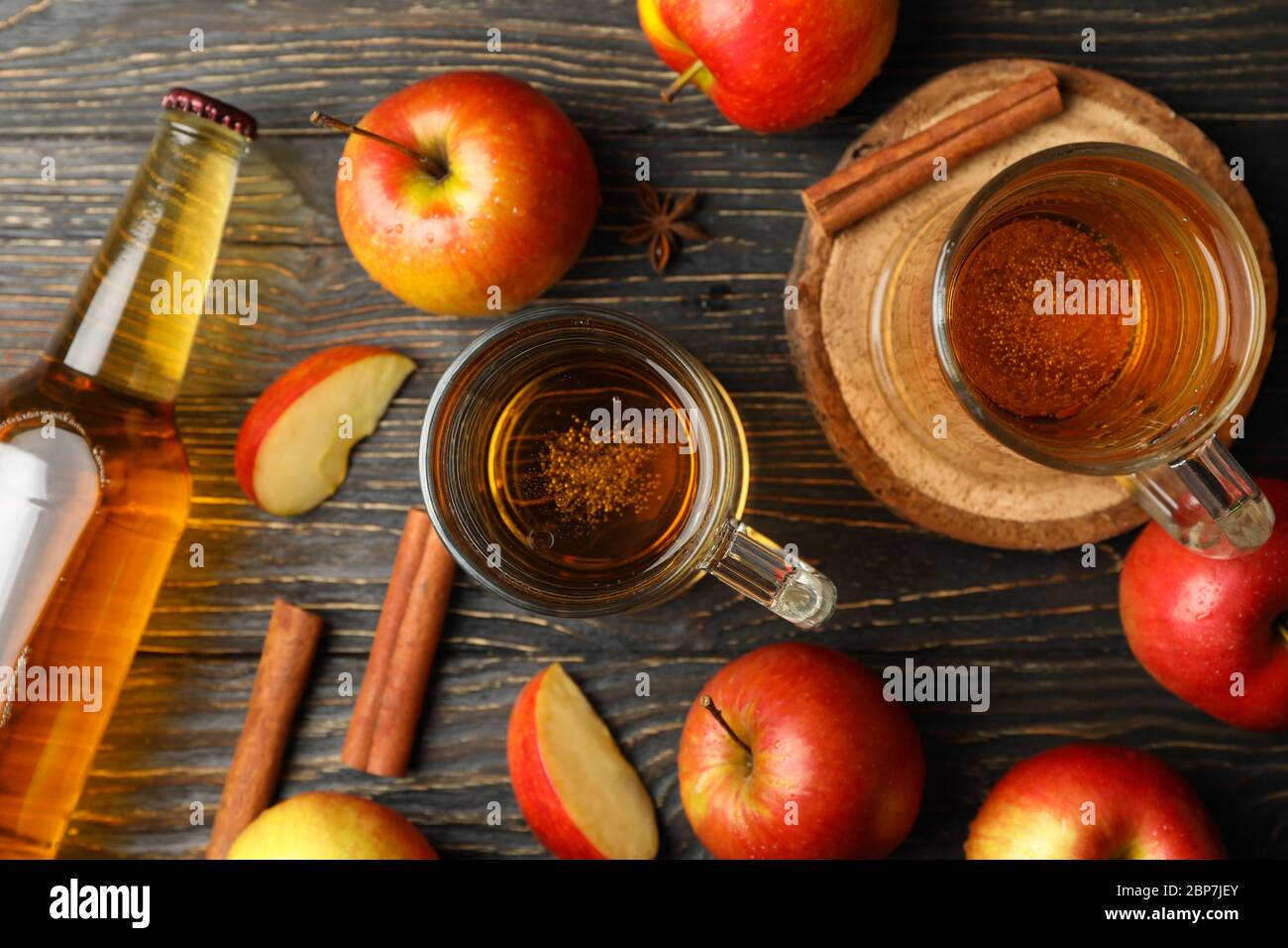 Composizione con sidro, cannella e mele su fondo ligneo Foto Stock