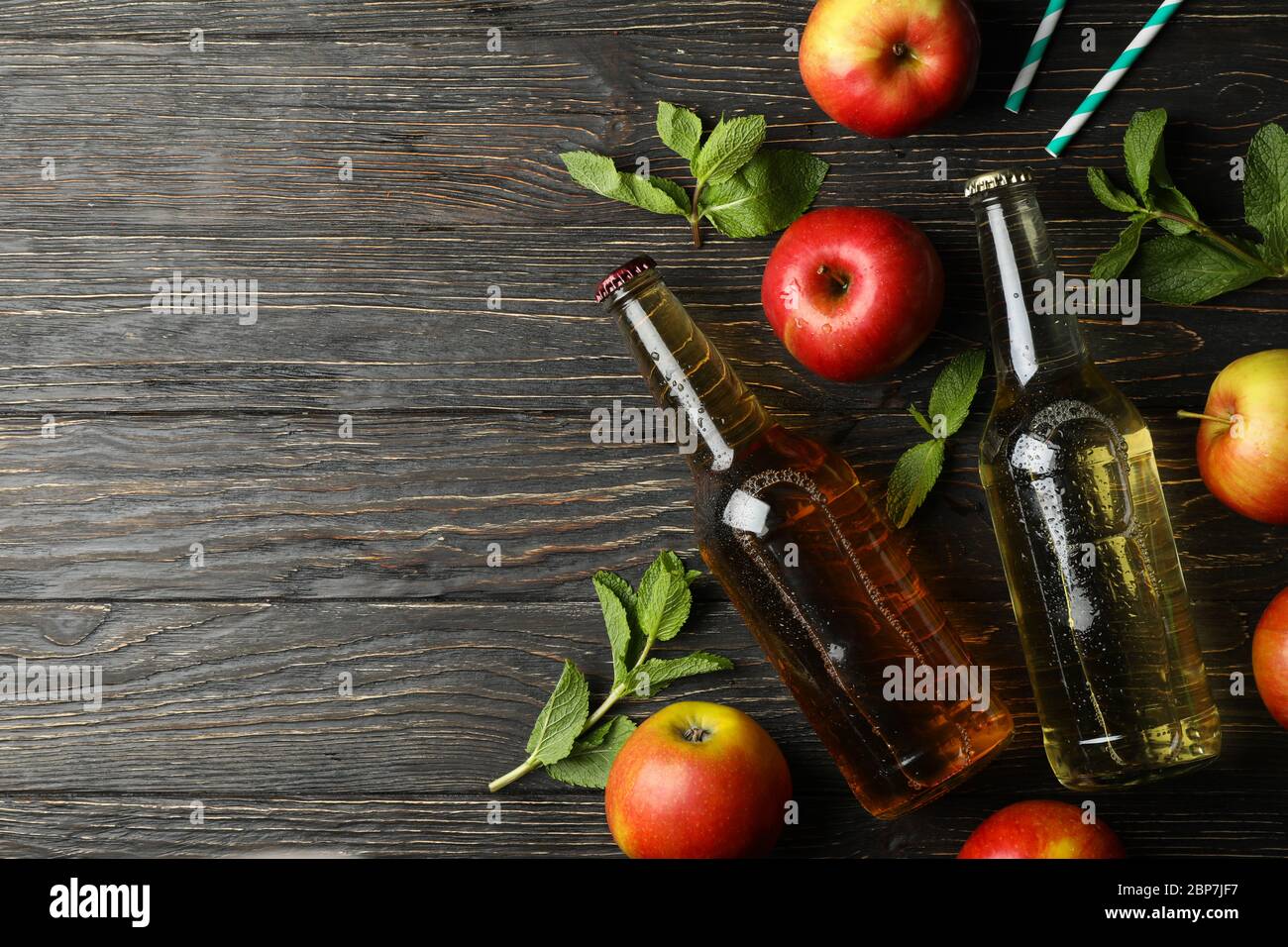 Composizione con sidro, mele e cannucce su fondo ligneo Foto Stock