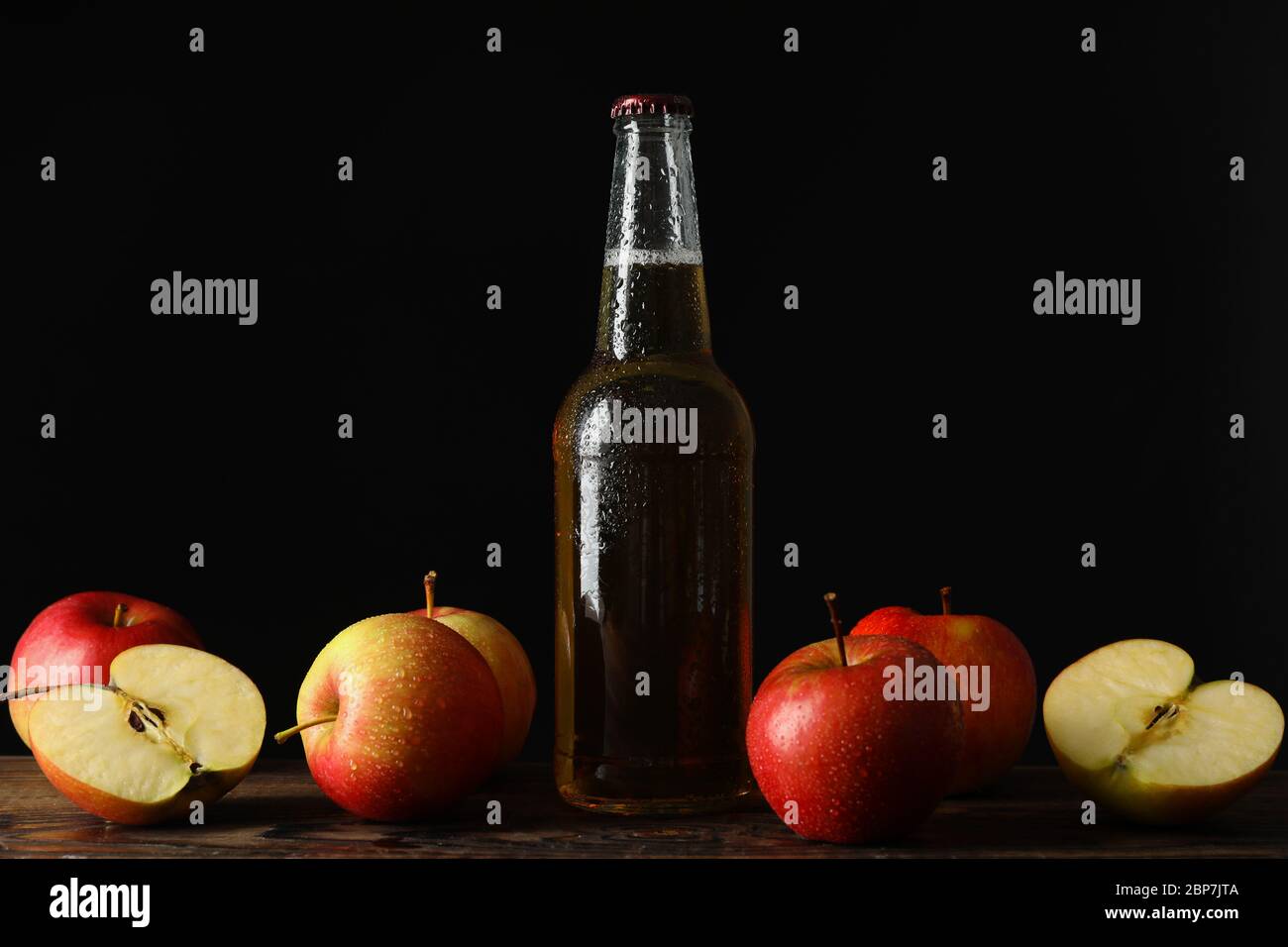 Composizione con sidro e mele su tavola di legno su fondo nero Foto Stock