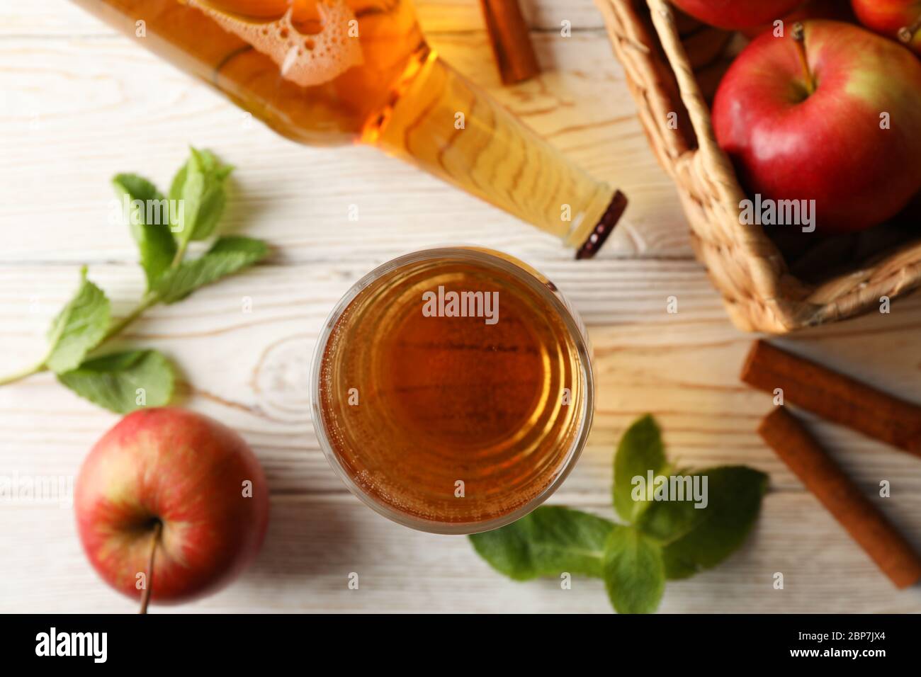 Composizione con sidro, cannella e mele su fondo di legno bianco Foto Stock