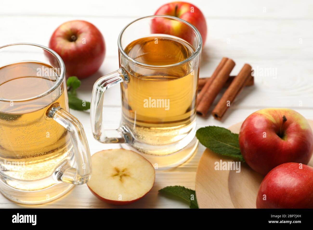 Composizione con sidro, cannella e mele su fondo di legno bianco Foto Stock