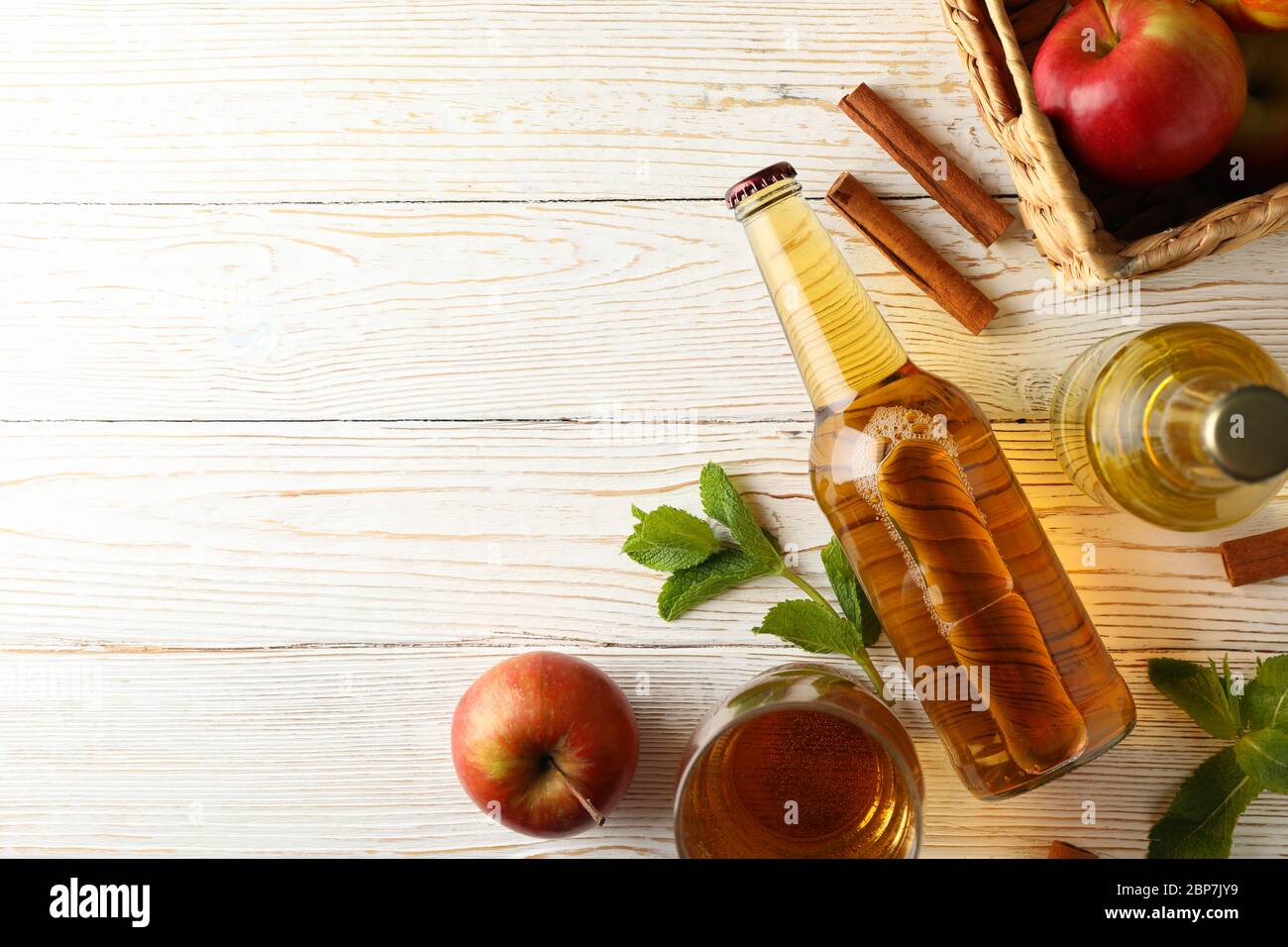 Composizione con sidro, cannella e mele su fondo di legno bianco Foto Stock