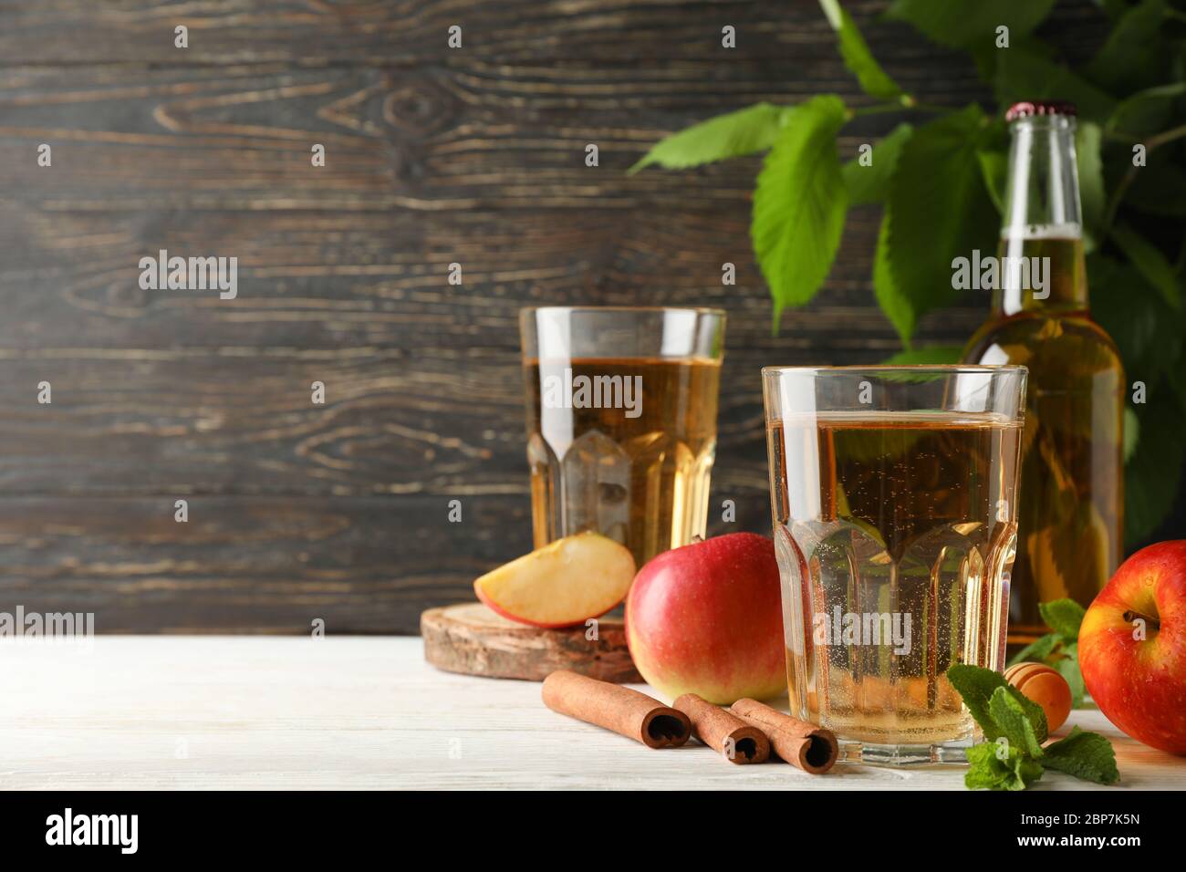Composizione con sidro, cannella e mele su fondo ligneo Foto Stock