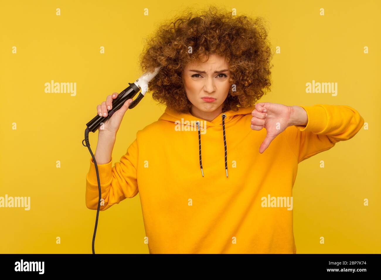 Donna dispiaciuta con il ferro arricciante per fare i capelli afro e  mostrare i pollici giù dislike, stirando i ricci dei capelli, esprimendo  insoddisfazione con anche Foto stock - Alamy