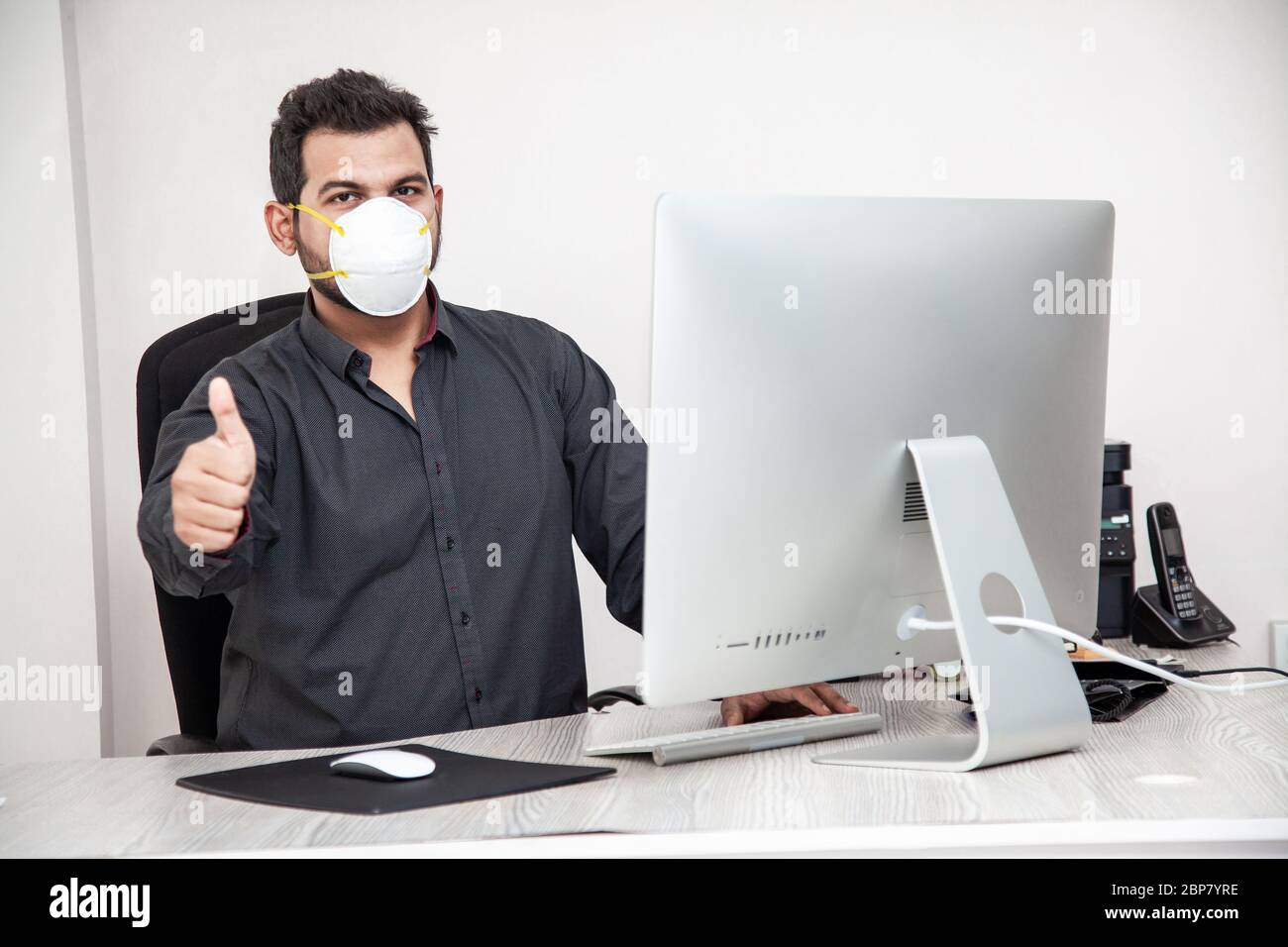 Uomo che ricopre il viso con maschera covid-19, ambiente di lavoro sicuro Foto Stock