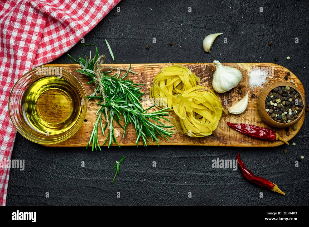 Ingredienti per la cucina italiana, pasta, erbe, spezie e olio d'oliva su tavola di pietra nera. Vista dall'alto con spazio per la copia. Foto Stock