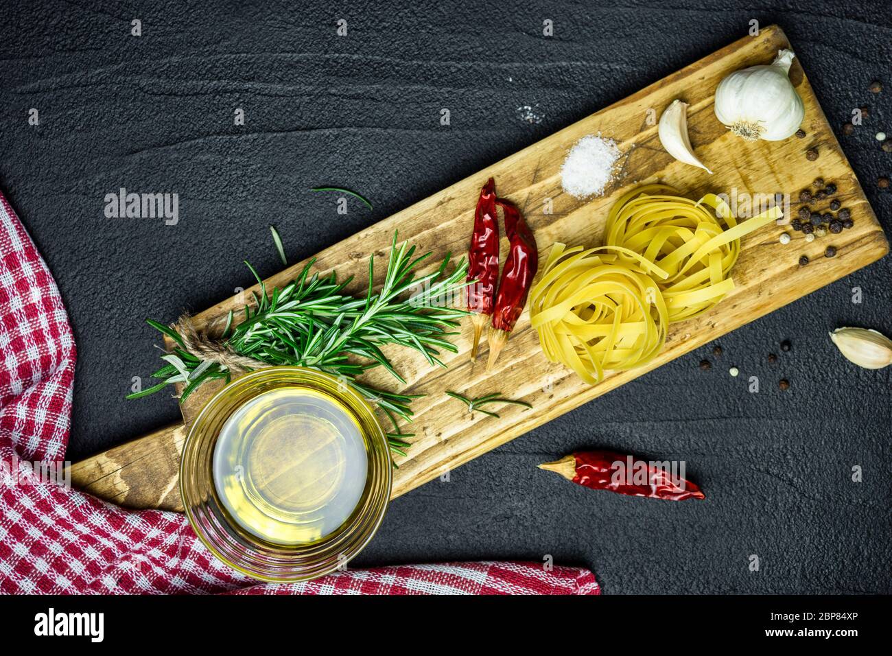 Ingredienti per la cucina italiana, pasta, erbe, spezie e olio d'oliva su tavola di pietra nera. Vista dall'alto con spazio per la copia. Foto Stock