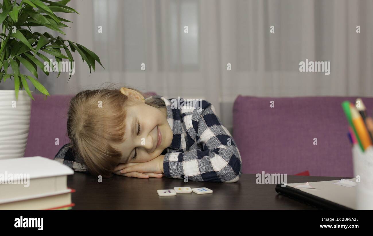 Bambina sfinito e dormire dopo le lezioni video online di lavoro a casa.  E-learning, webinar. Formazione online a distanza per i bambini causati  dalla quarantena di pandemia di coronavirus Foto stock -