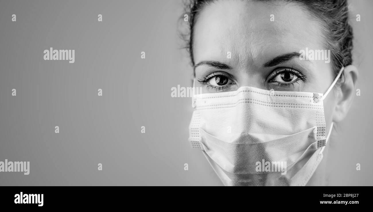 Nero e bianco banner panoramico foto di una Donna Dottore in una maschera chirurgica protettiva contro il coronavirus su uno sfondo chiaro menta. Banner panorama personale medico attrezzatura preventiva. Modifica spazio copia. Foto Stock