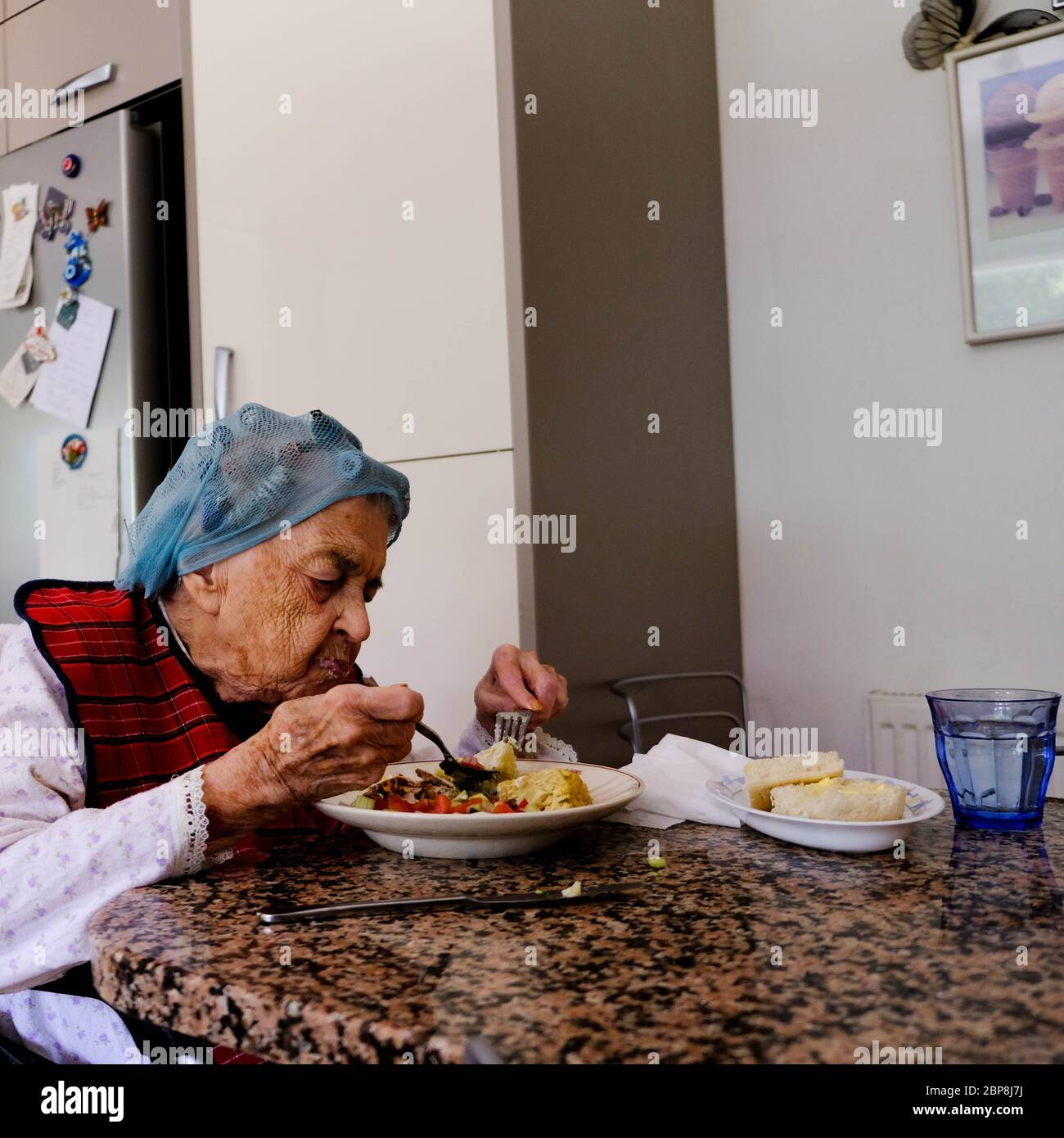 Donna anziana che mangia da sola, autoisolando durante il blocco britannico di Coronavirus, che mangia UN pasto Foto Stock