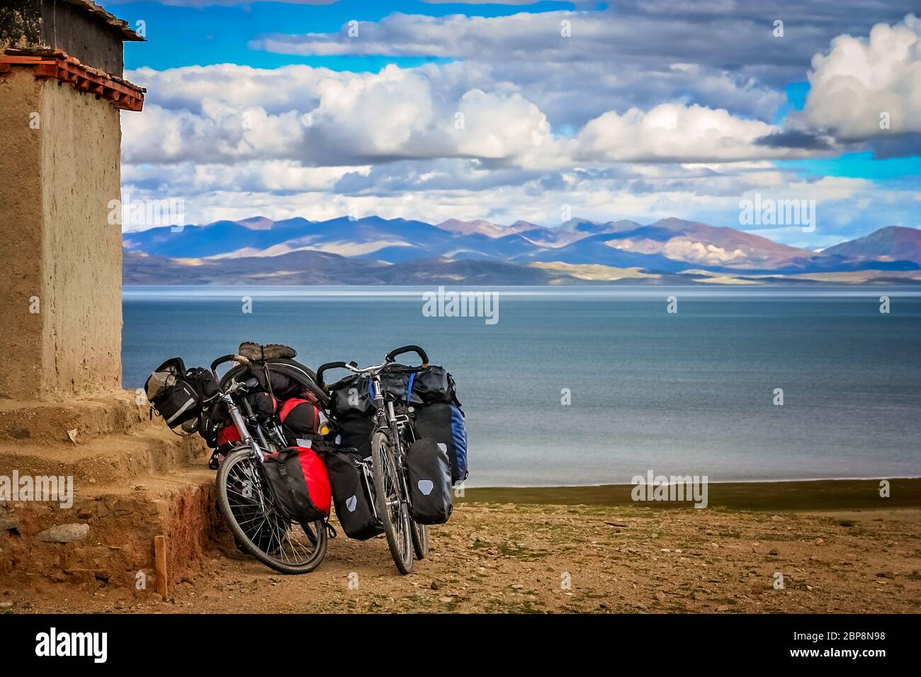 Due cicloturismo caricato le biciclette appoggiata sulla parete di un piccolo vecchio monastero tibetano su una collina sopra il Lago Santo Manasarovar, Tibet, Cina Foto Stock