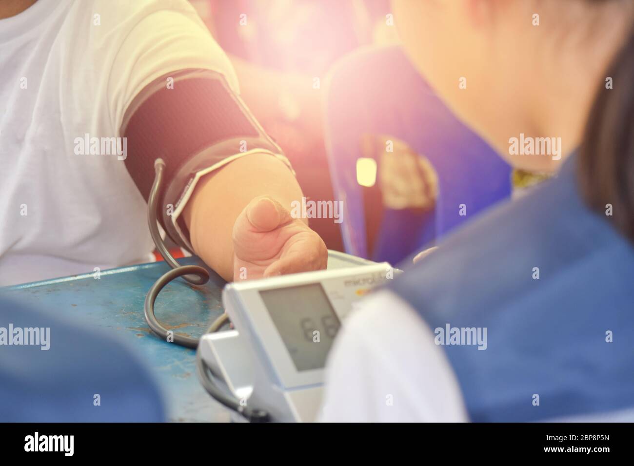 Primo piano di un medico femminile che controlla la pressione sanguigna di un paziente di sesso maschile. Unità medica mobile e trattamento ambulatoriale, luogo Foto Stock