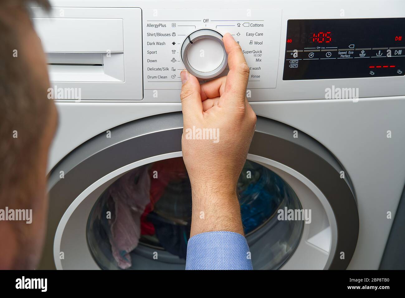L'operatore imposta il programma e accende la lavatrice. Primo piano di  persona premendo a mano il pulsante della lavatrice per vestiti lavanderia  Foto stock - Alamy