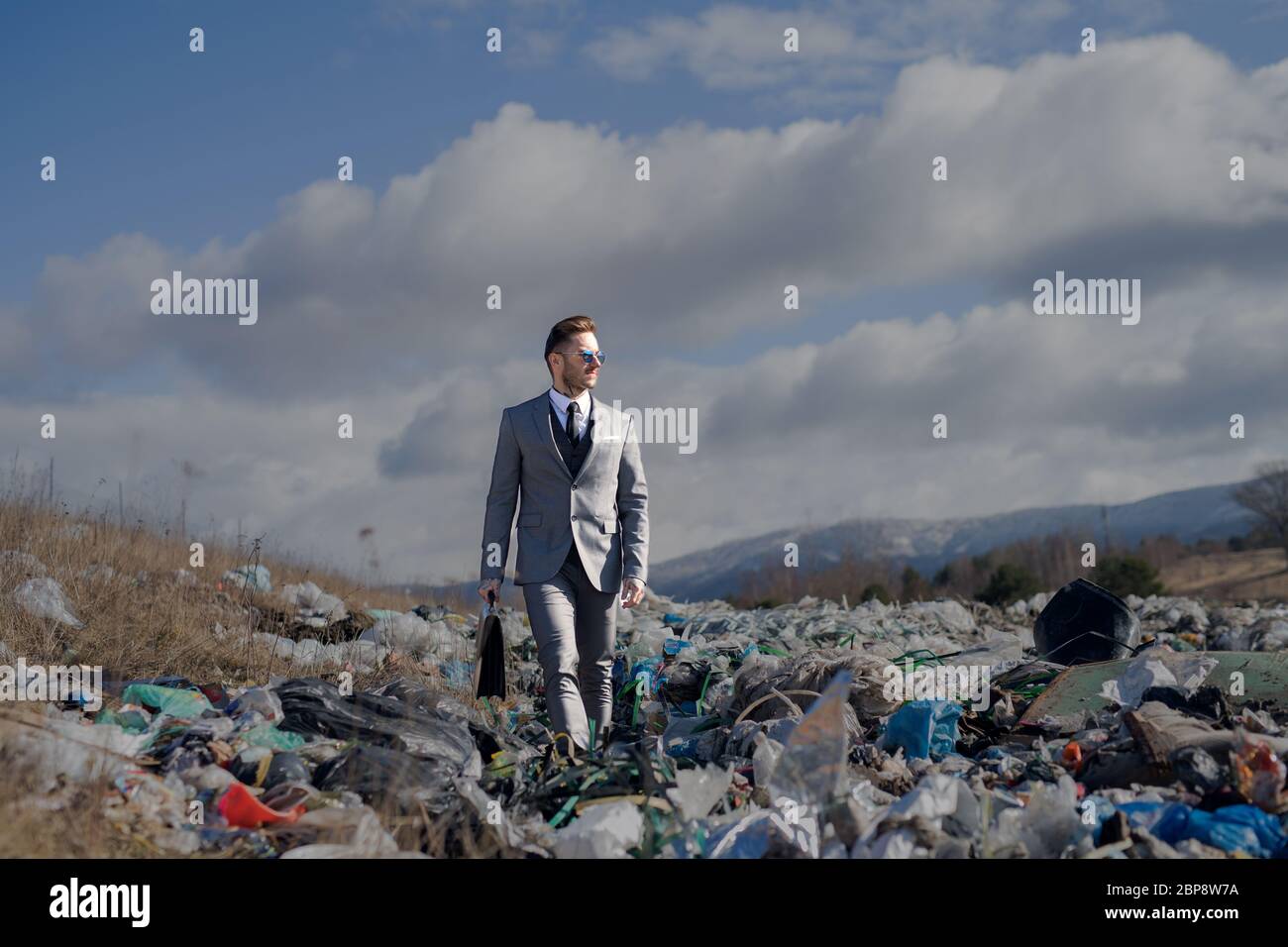 Uomo d'affari moderno in discarica, consumismo contro concetto di inquinamento. Foto Stock