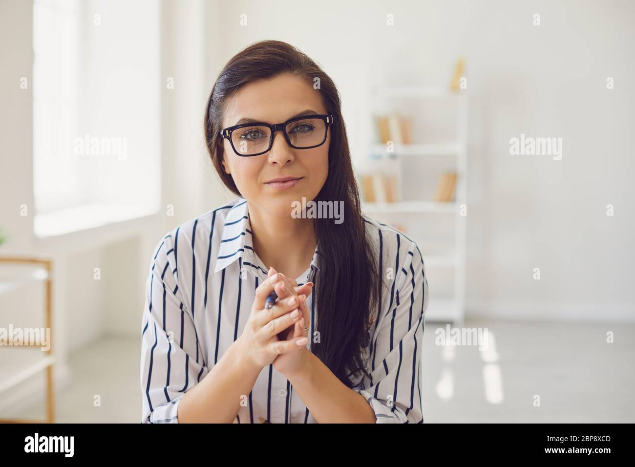 Insegnante ispanico con occhiali che guardano la macchina fotografica sorridendo. Un insegnante universitario insegna in remoto utilizzando un gadget applicativo per videochiamata. Foto Stock