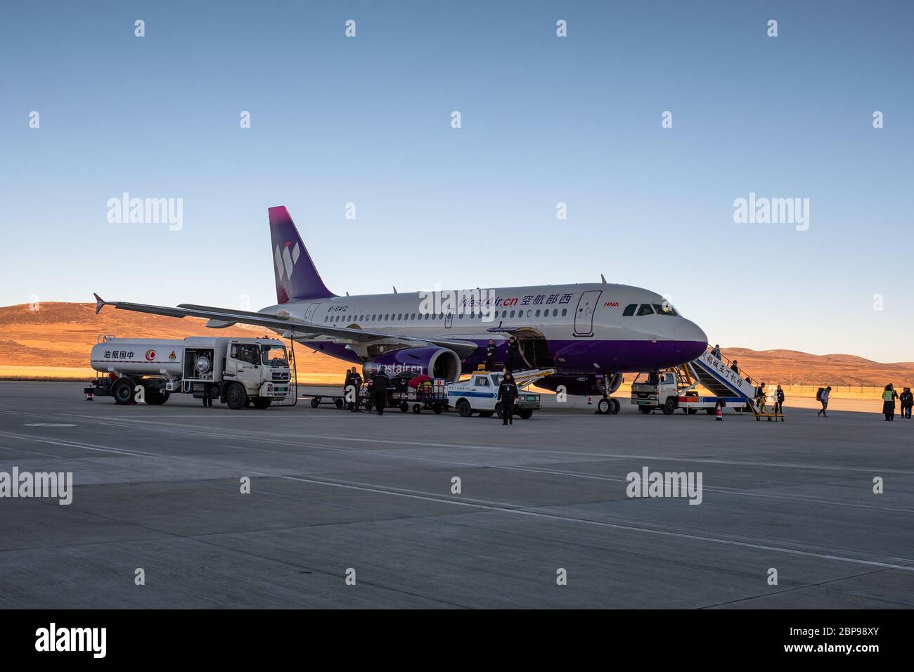 Daocheng, Cina - Ott 25 2018 : aereo aereo aereo aereo aereo la compagnia aerea cinese con i turisti discendono dalla cabina e ufficiale si prepara per il rifornimento sulla pista Foto Stock