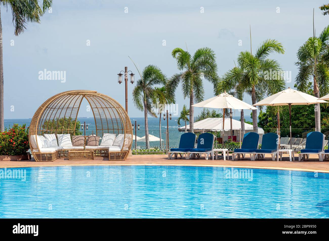 Pattaya, Thailandia - Maggio 26 2019 : lettini blu con ombrellone con moderna sedia in legno sulla piscina in mare tropicale Foto Stock
