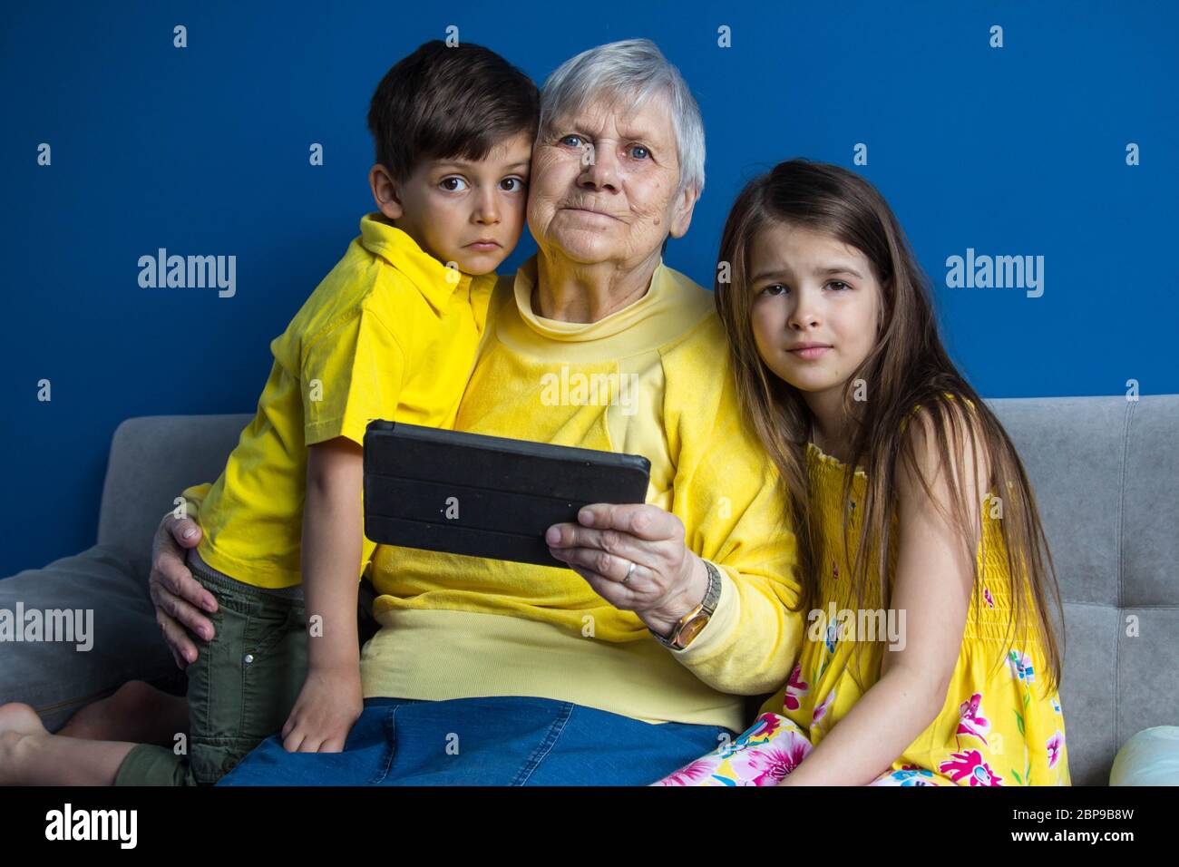Una vecchia nonna e i suoi amati nipoti si siedono a casa e parlano al telefono Foto Stock