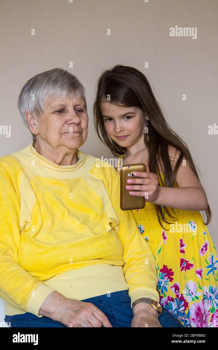 Una vecchia nonna e i suoi amati nipoti si siedono a casa e parlano al telefono Foto Stock