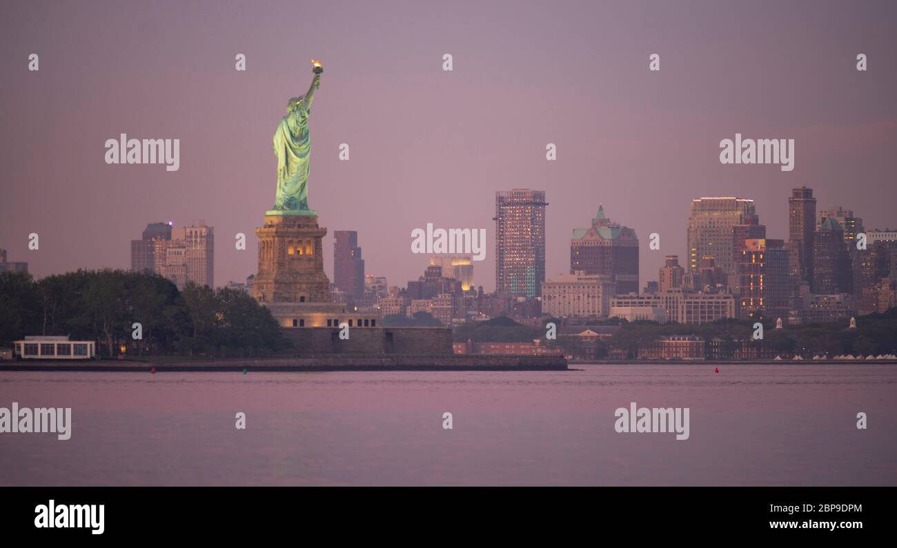 La Statua della Libertà dopo il tramonto con Brooklyn New York in background Foto Stock