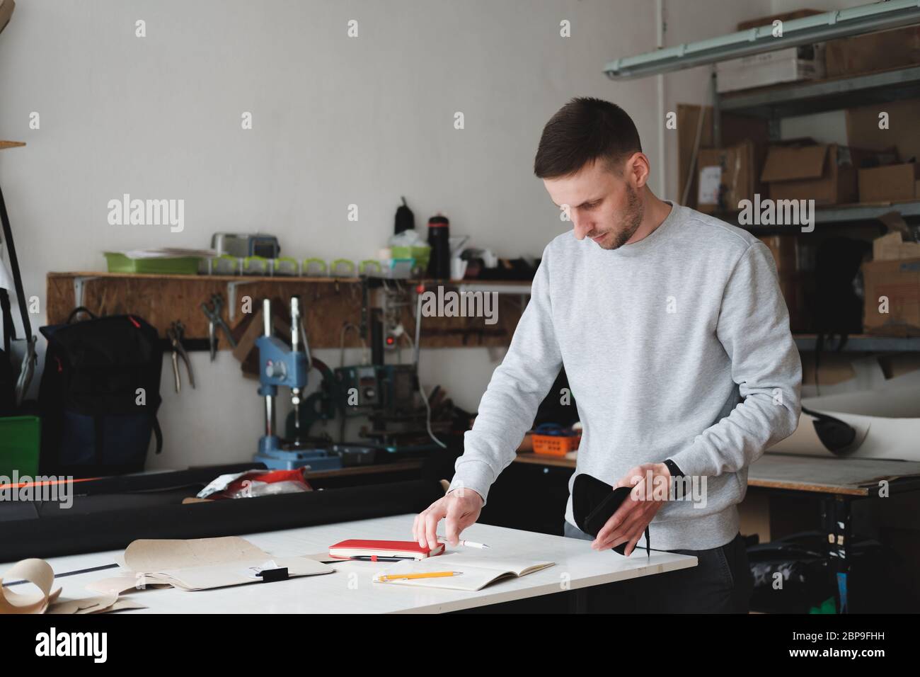 Ritratto di un progettista o ingegnere di abbigliamento in un'officina generica. Piccola impresa, imprenditore locale, concetto di sviluppo della moda Foto Stock