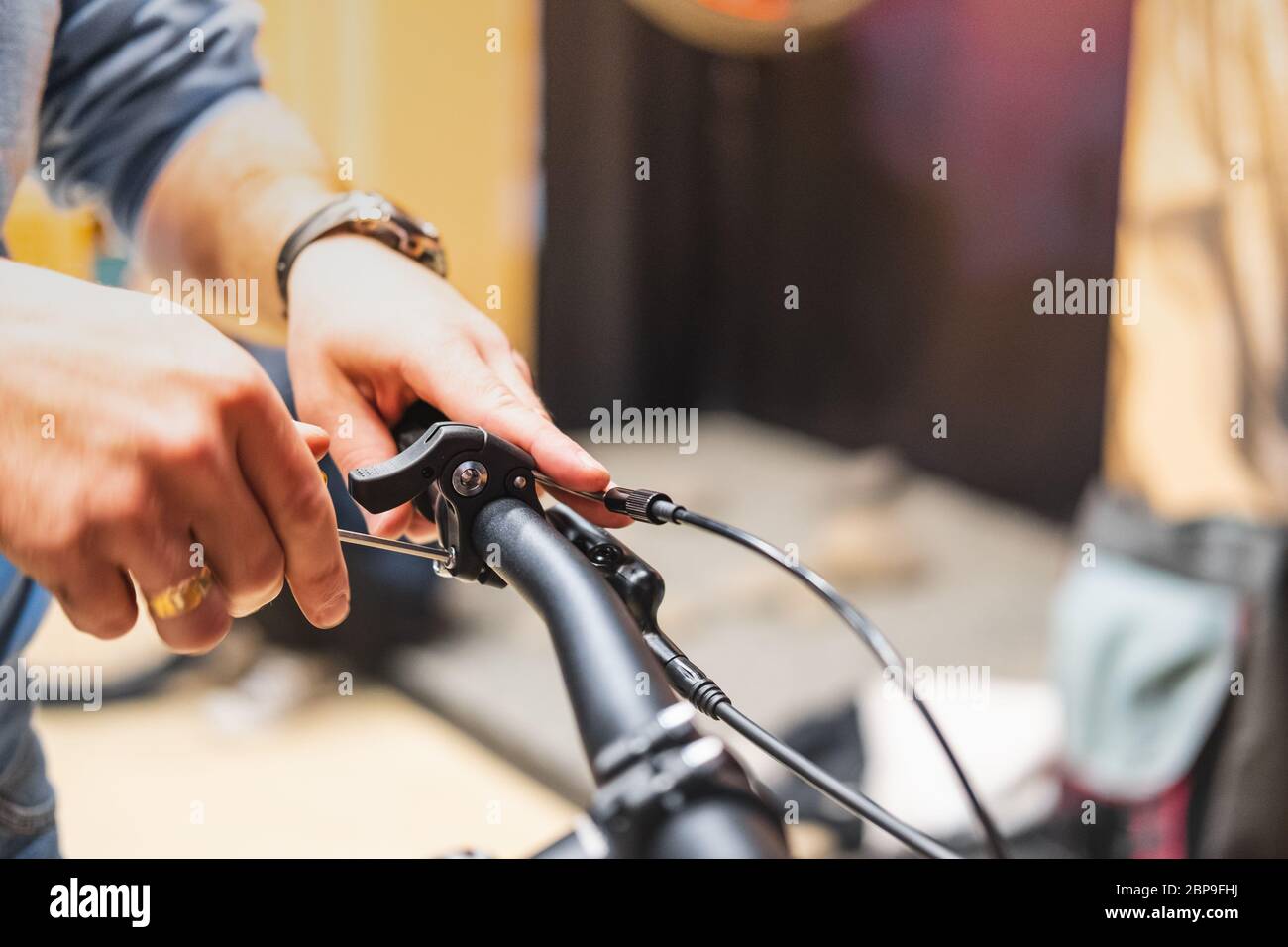 Impostazione delle pause di una bicicletta, vista ravvicinata. Mani umane che riparano una bicicletta in un negozio locale di biciclette Foto Stock
