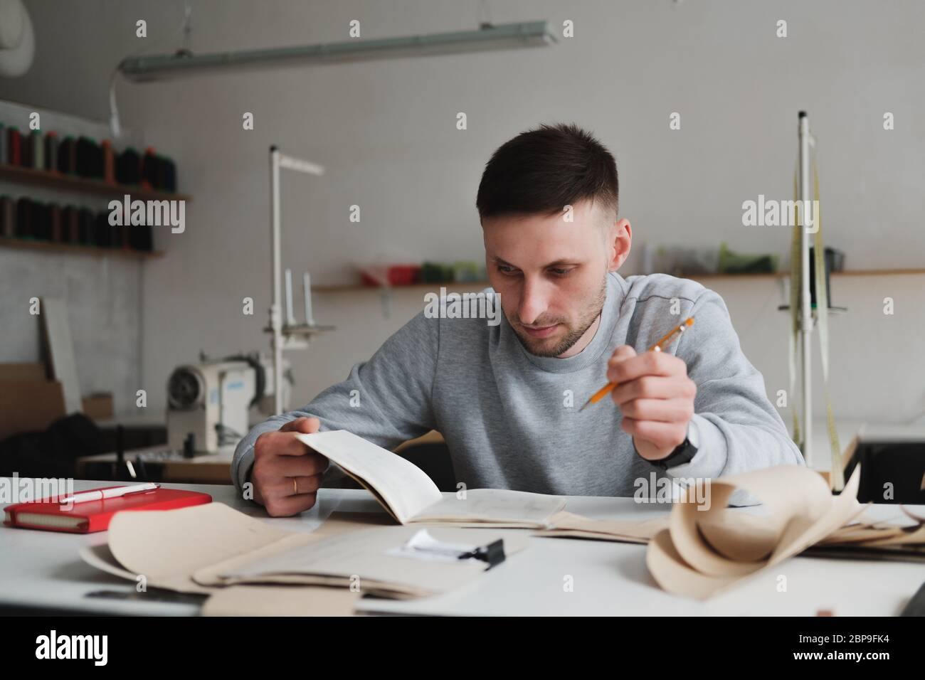 Uomo che lavora in ingegneria o che gestisce un lavoro in un'officina generica. Piccola impresa locale, ritratto di designer di abbigliamento Foto Stock