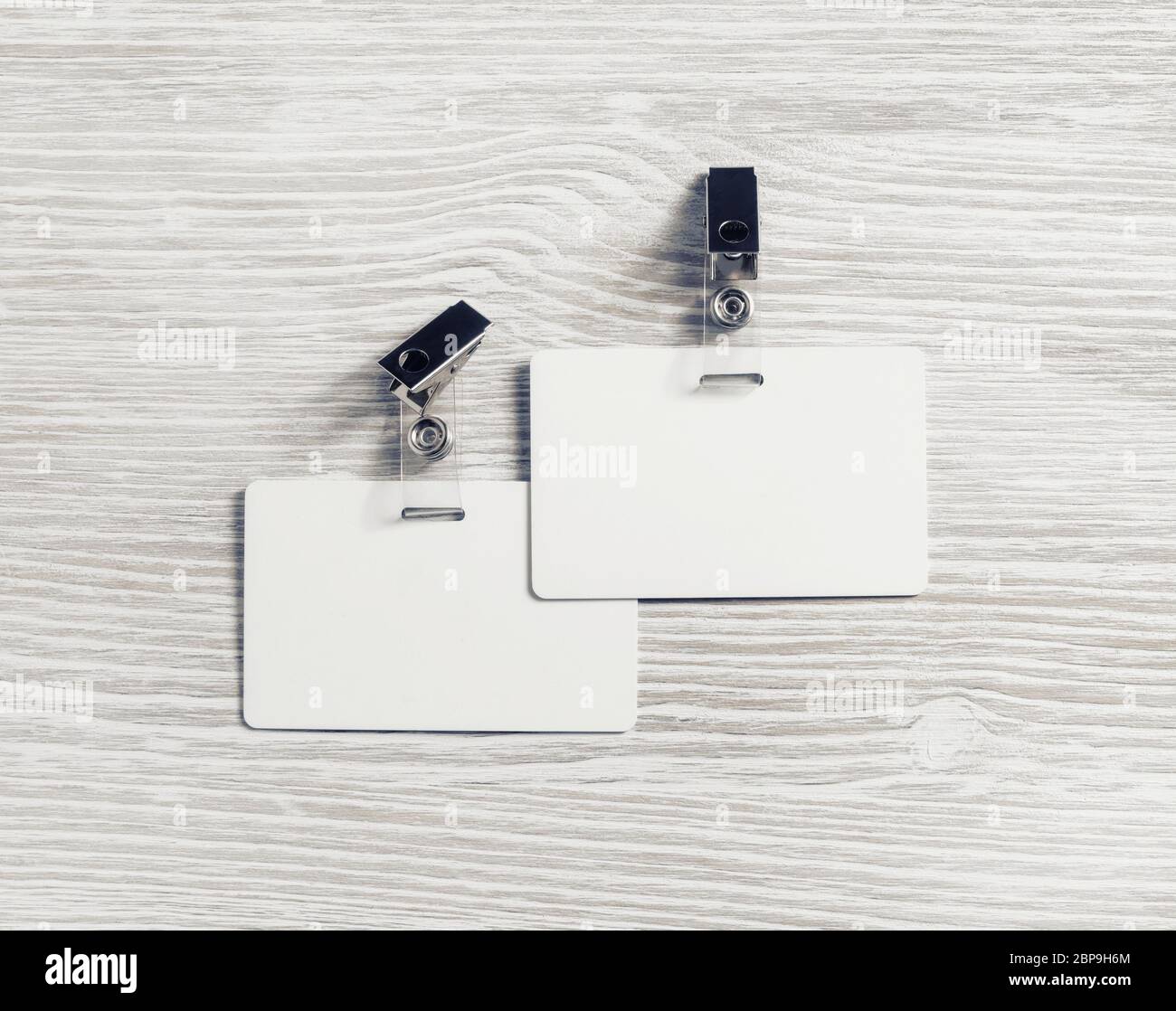 Due blank badge in plastica mockup su legno chiaro sfondo tabella. Empty ID mock up. Copia spazio per il testo. Lay piatto. Foto Stock