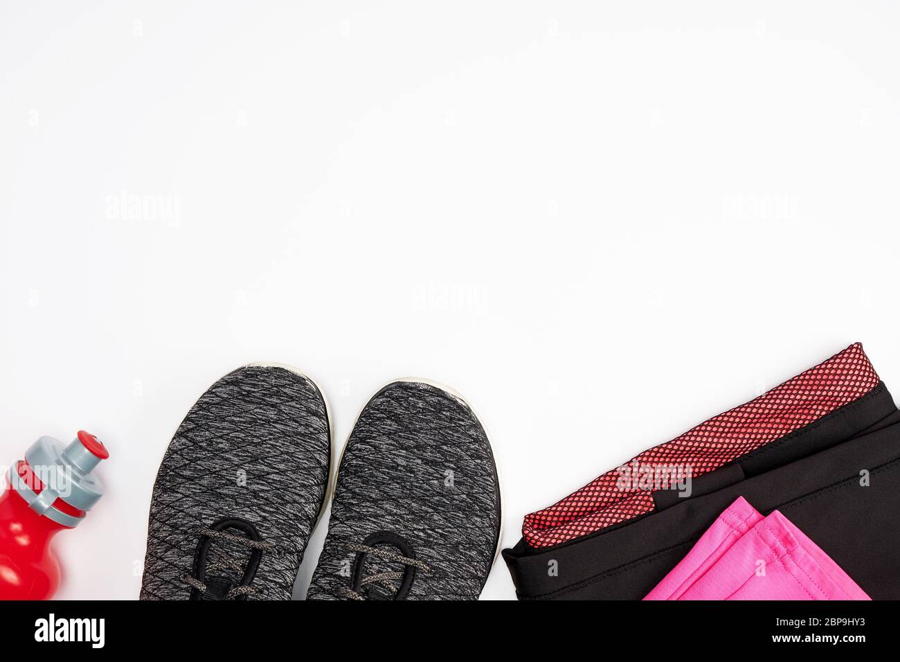 Tessuto nero scarpe e altri elementi per il fitness su uno sfondo bianco, vista dall'alto Foto Stock