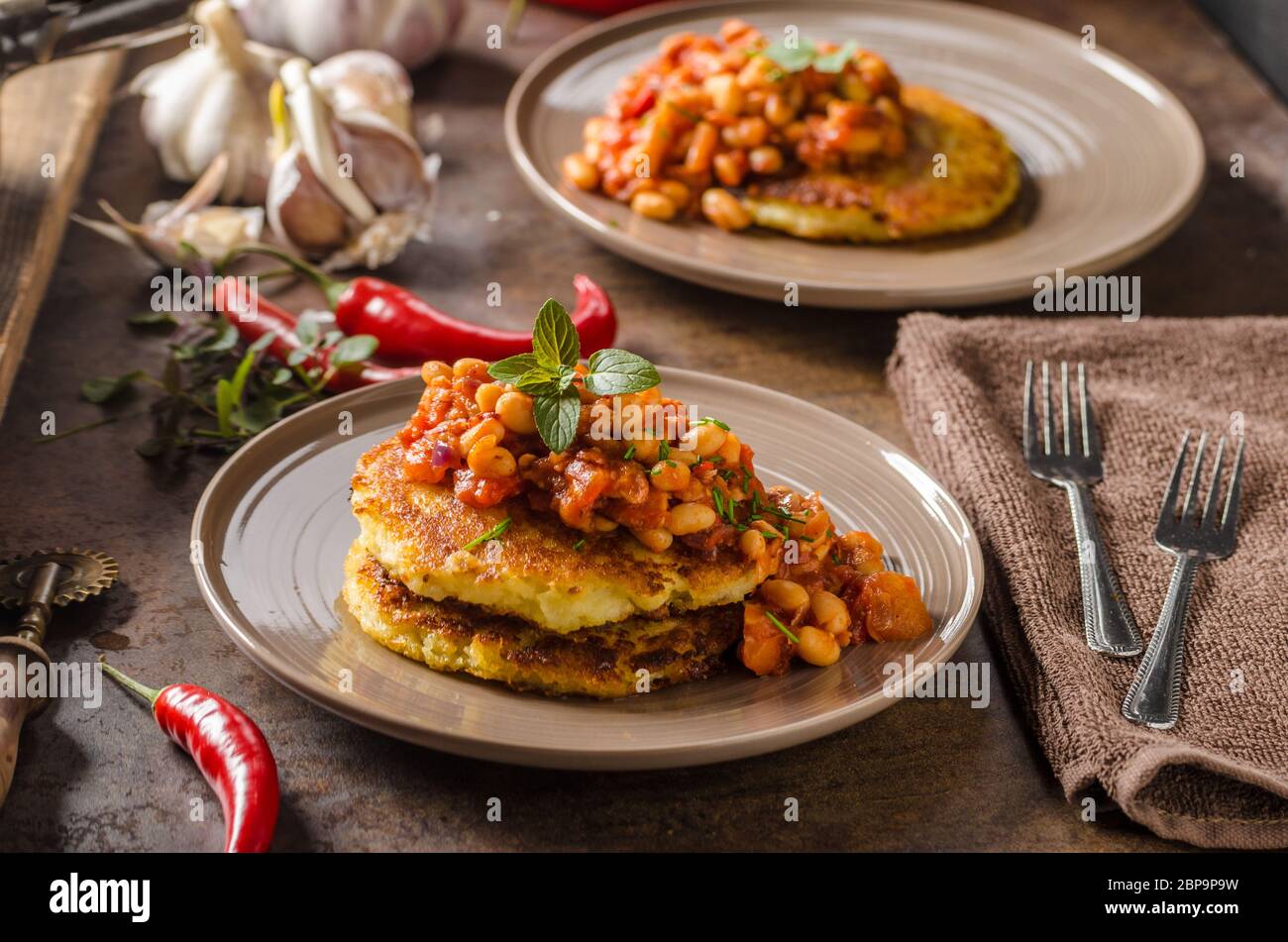 Cuocere i fagioli con soffici torte di patate, speziato e una deliziosa prima colazione Foto Stock