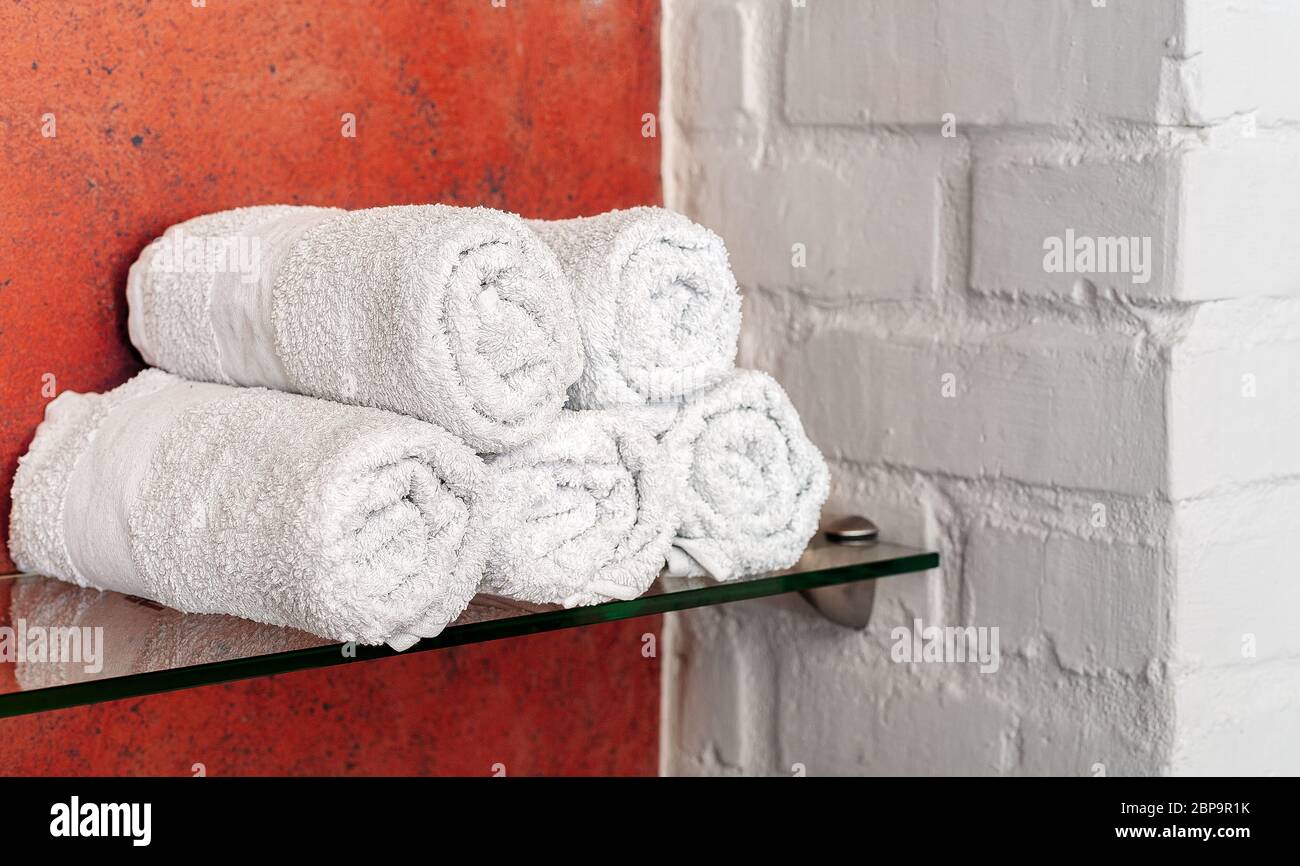 Asciugamani bianchi in rotoli sul ripiano in bagno, salone di