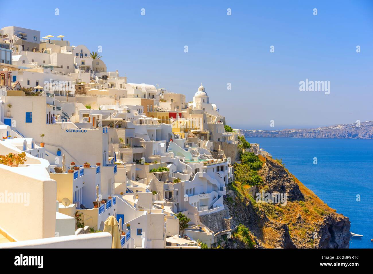 Il sole splende sulle idilliache chiese e case costruite sul bordo della Caldera a Thira, Santorini Foto Stock
