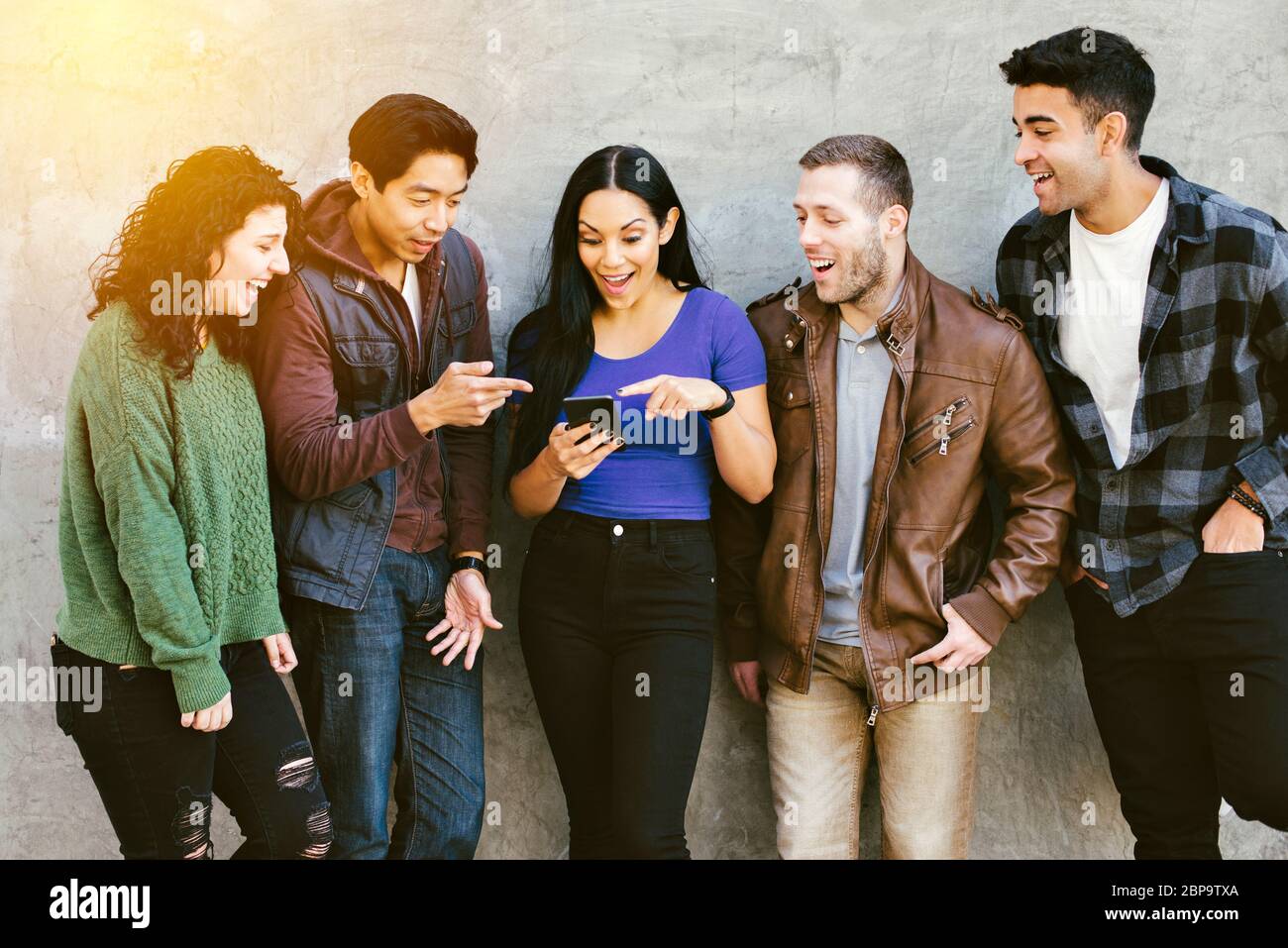 I giovani adulti reagiscono a uno smartphone in città - diversi - Social Media - Gossip - Shaming Foto Stock