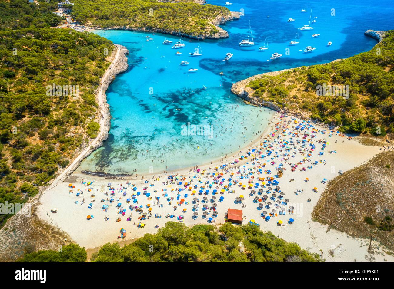 Vista aerea della spiaggia sabbiosa con ombrelloni, barche in baia Foto Stock