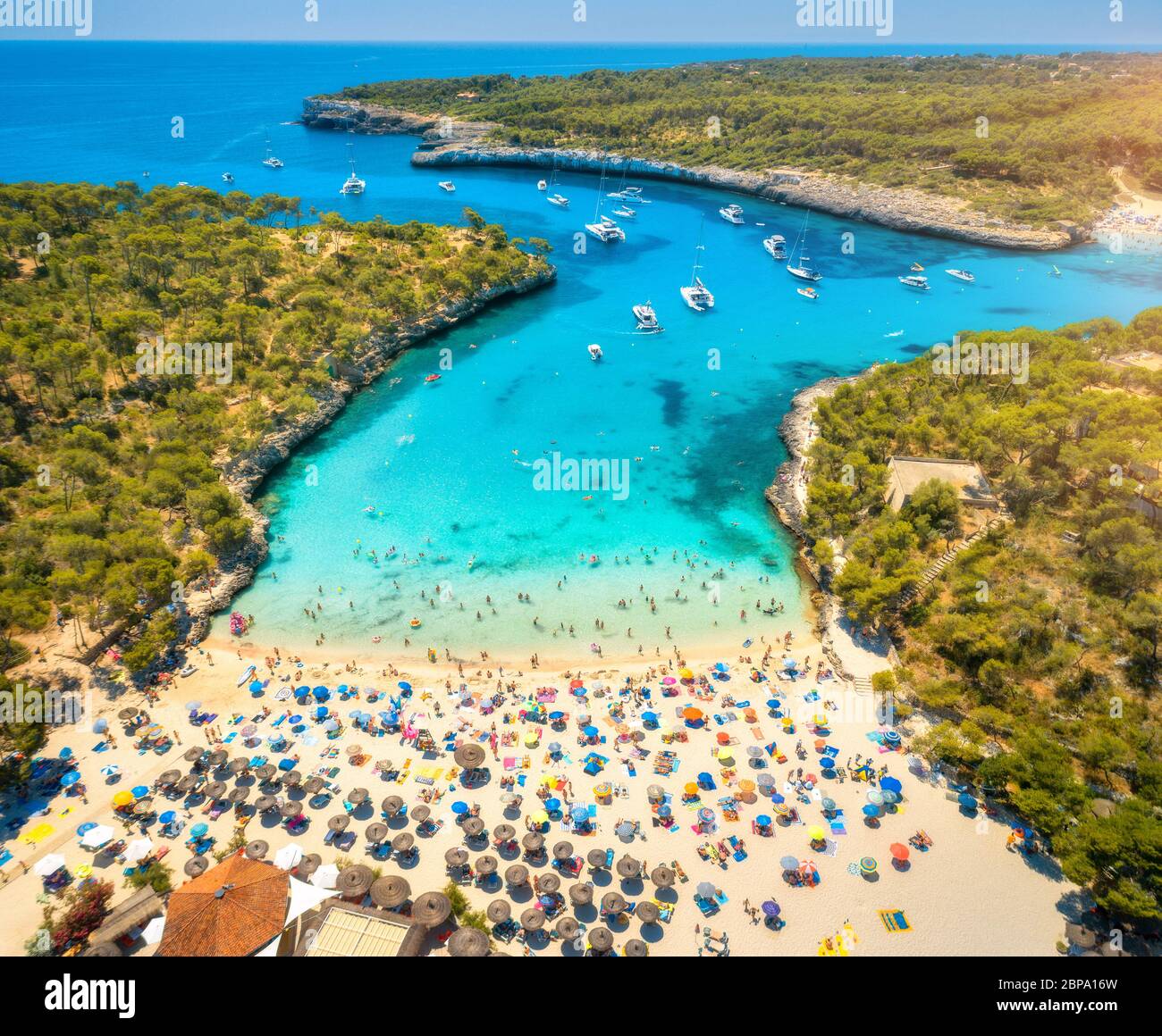 Vista aerea della spiaggia sabbiosa con ombrelloni, barche in baia Foto Stock