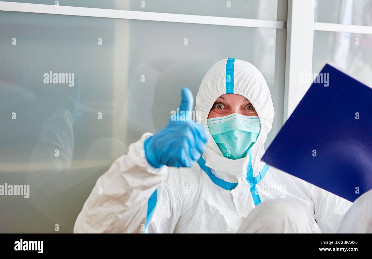 La scout di contenimento con indumenti protettivi tiene i pollici in su durante la pandemia del coronavirus Foto Stock