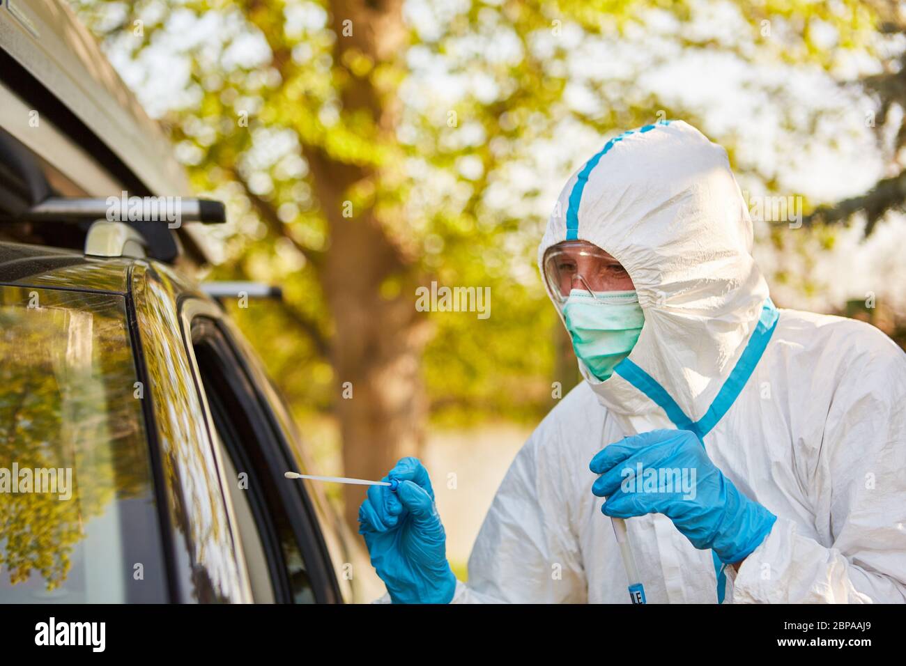 Test del coronavirus con tampone alla gola nella stazione di test drive-in da parte dei dipendenti del reparto sanitario Foto Stock