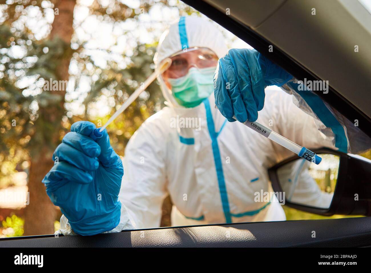 Lo scout di contenimento del reparto sanitario tiene un tampone alla gola da un test del coronavirus in una stazione di test drive-in Foto Stock
