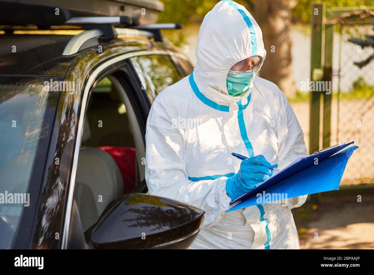 Dipendente come contenitore scout cattura i visitatori in auto dalla casa di cura alla lista delle visite durante la pandemia di coronavirus Foto Stock