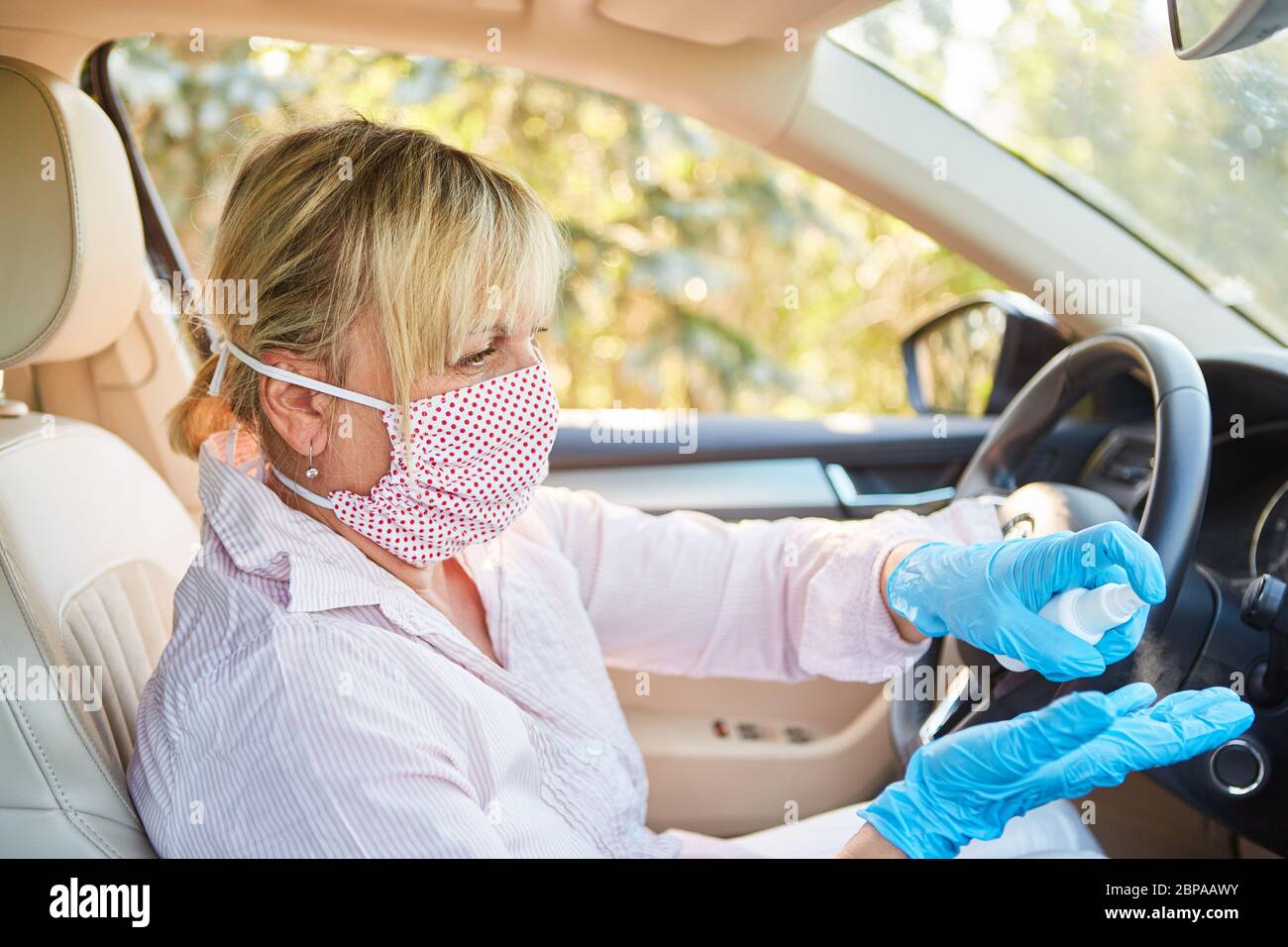 Pulitore con maschera viso utilizza disinfettante in auto a noleggio a causa di pandemia coronavirus Foto Stock