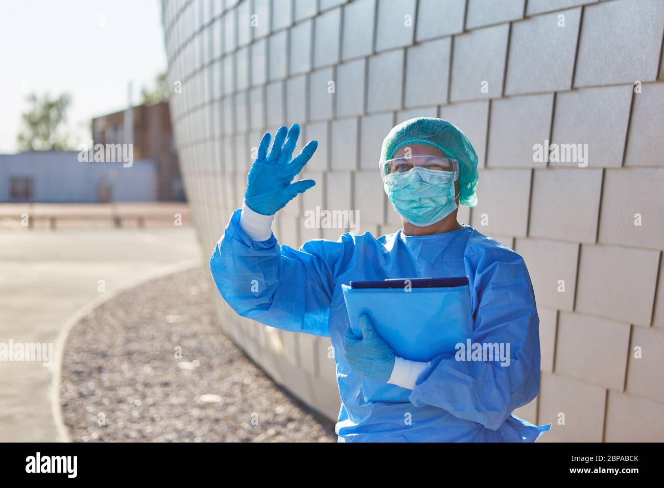 Il personale infermieristico o lo scout di contenimento con elenco per il tracciamento dei contatti fornisce un segnale di arresto di fronte alla clinica durante la pandemia di coronavirus Foto Stock