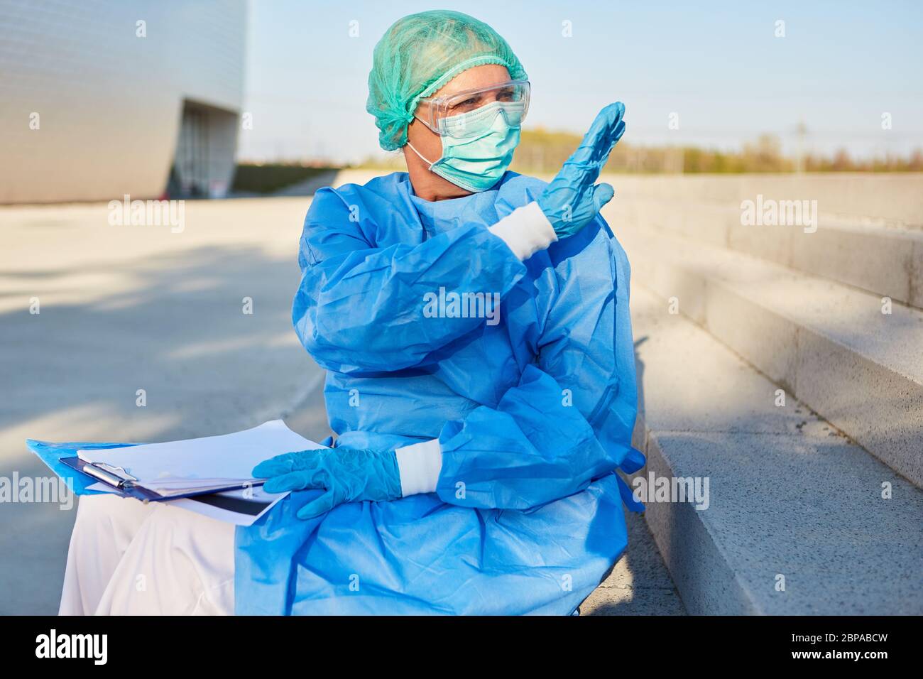 Il personale infermieristico o lo scout di contenimento con elenco per il monitoraggio dei contatti crea segni di arresto di fronte alla clinica durante la pandemia di coronavirus Foto Stock