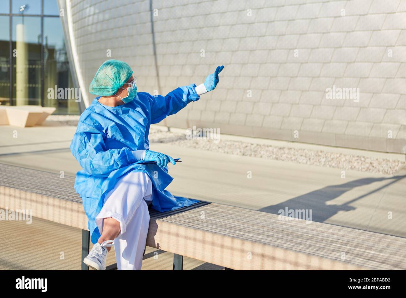 Lo scout di contenimento con elenco per il tracciamento dei contatti fornisce segnali manuali davanti alla clinica per l'ammissione alla pandemia del coronavirus Foto Stock