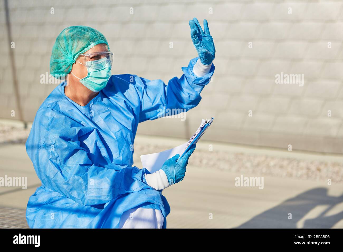 Personale infermieristico o scout di contenimento con elenco per il monitoraggio dei contatti sollecita ad attendere di fronte alla clinica per pandemia di coronavirus Foto Stock