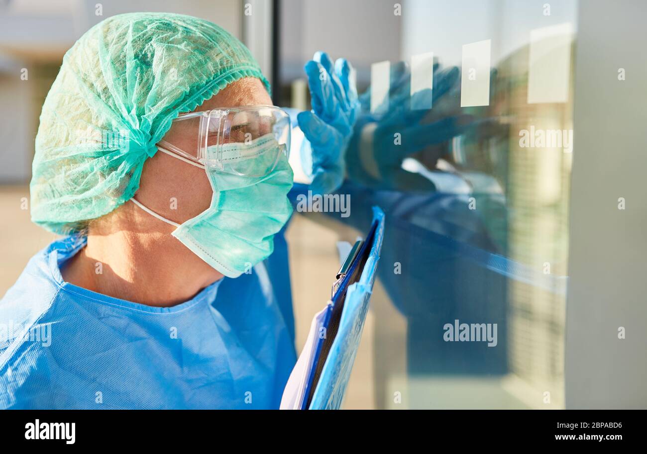 Il personale infermieristico o lo scout di contenimento con elenco per il tracciamento dei contatti fornisce segnali manuali davanti alla clinica durante la pandemia di coronavirus Foto Stock